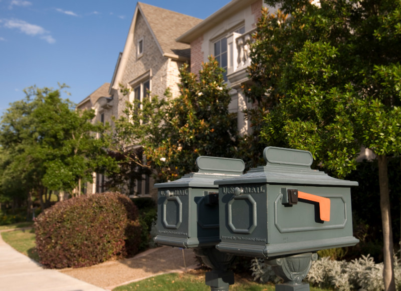 Two mail boxes and a house in the background